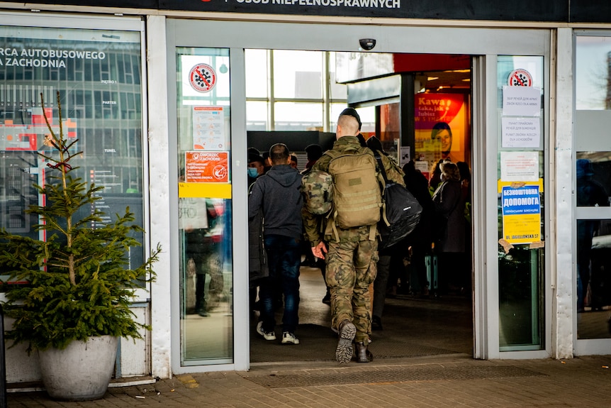 A group of men walk into a shop dressed in army fatigues.