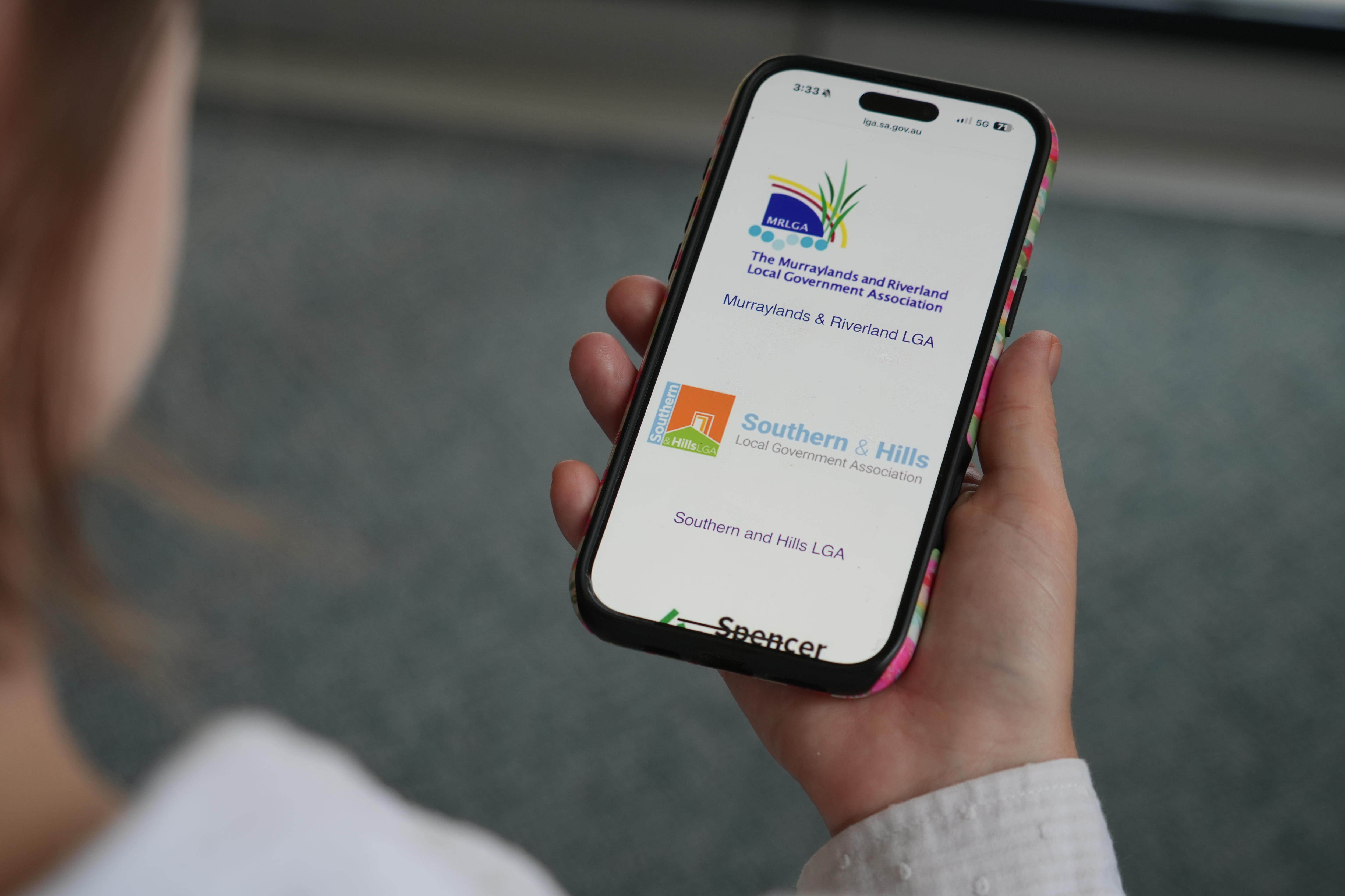 Женщина, вид из-за плеча, держит телефон.