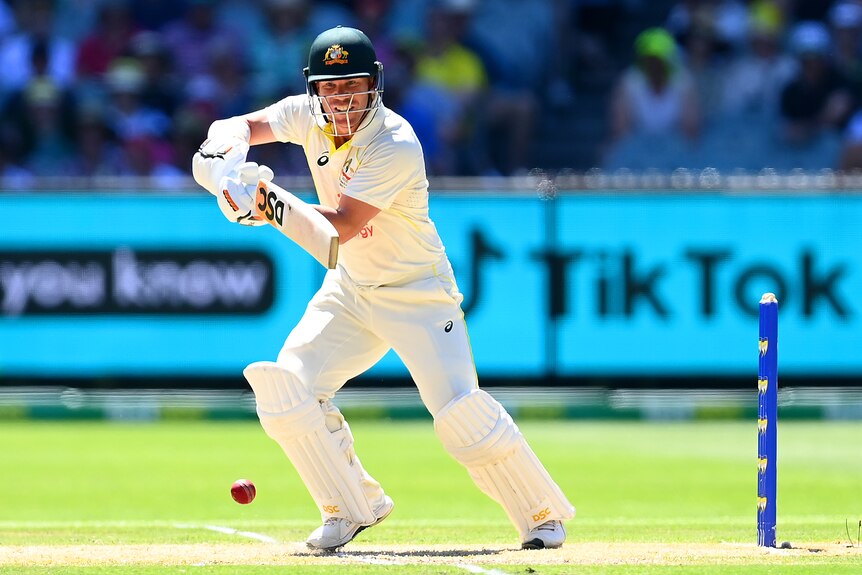 David Warner looks at the ball as he plays a shot with a crossed bat