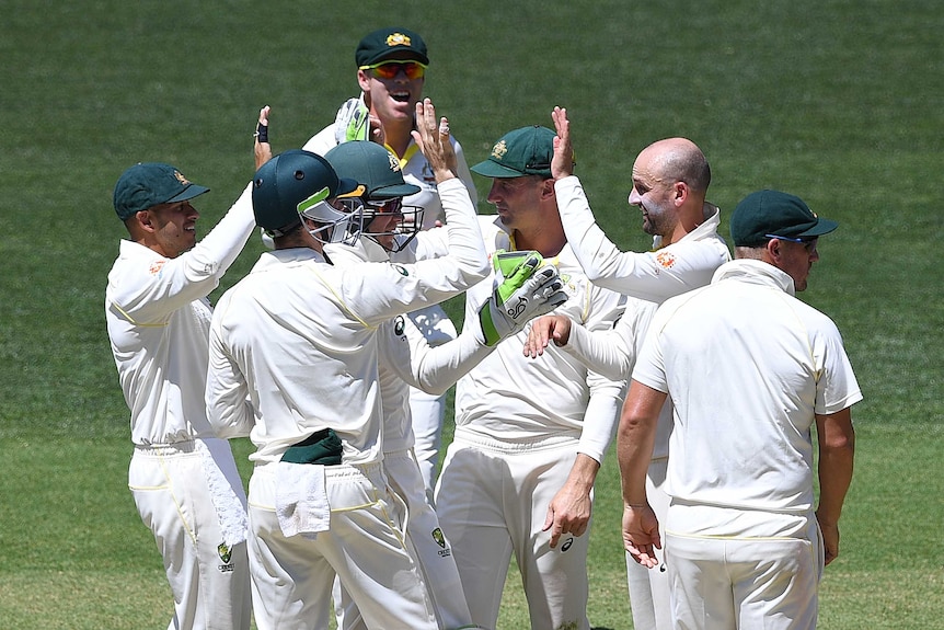 Nathan Lyon is congratulated by his cricket colleagues