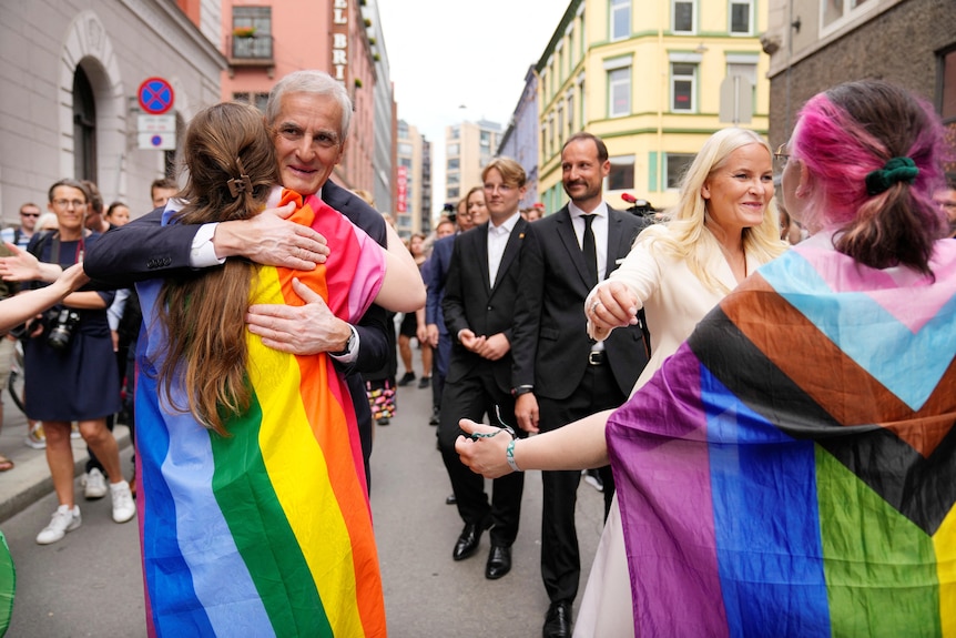 拥抱人们，有些人戴着 LGBT 旗帜