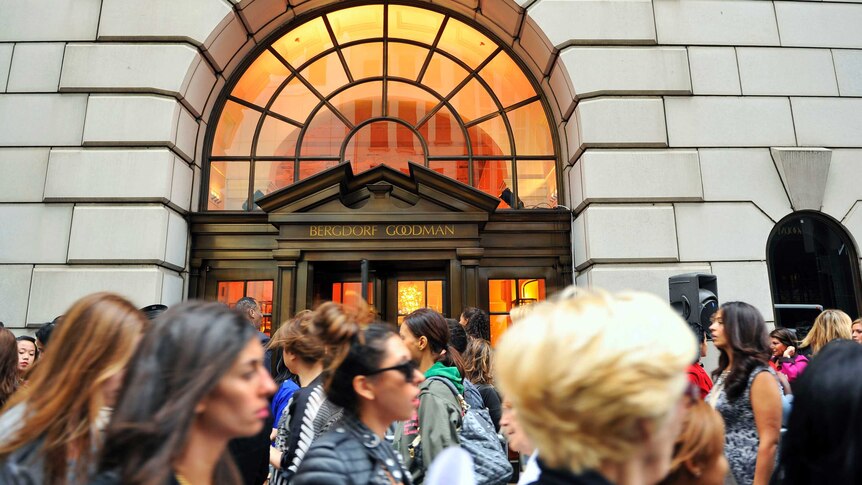 A large crowd of people stand in front of the Bergdorf Goodman store in New York City.