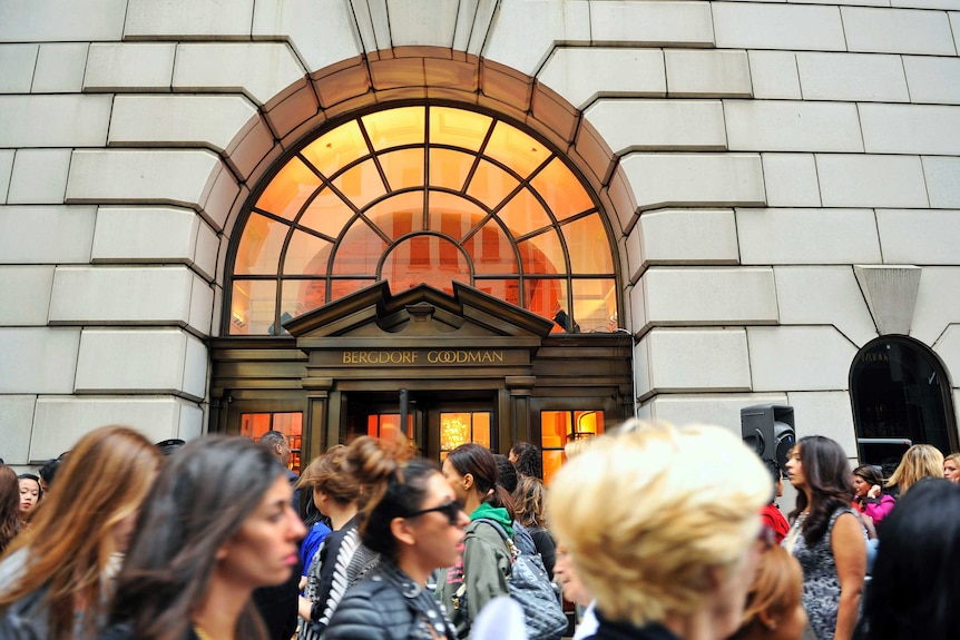 A large crowd of people stand in front of the Bergdorf Goodman store in New York City.