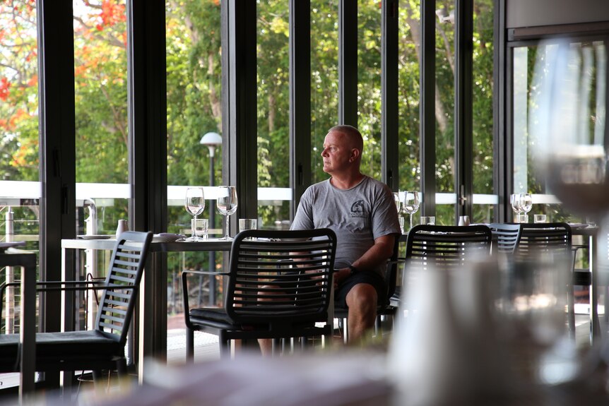 Restaurateur Simon Matthews sits at a table on his empty restaurant floor, looking out the window. 
