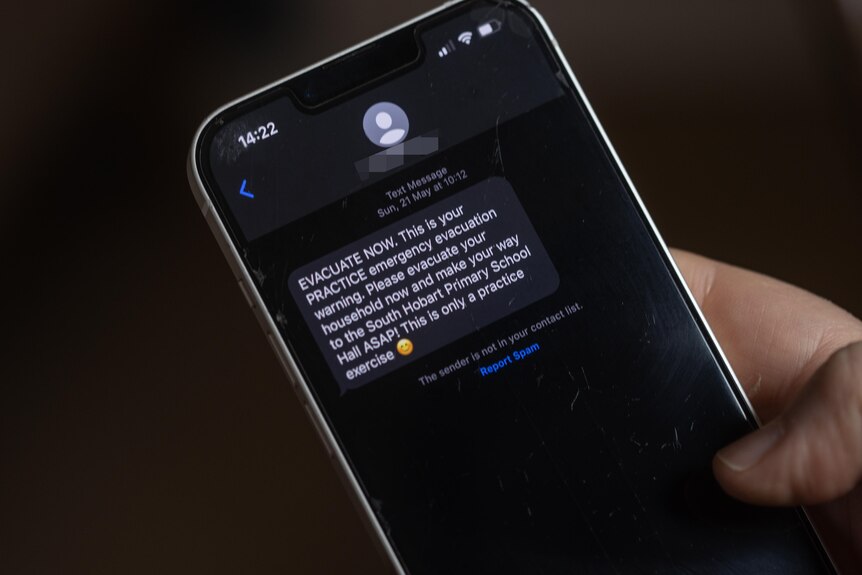 A hand holds a mobile phone with a text message on the screen