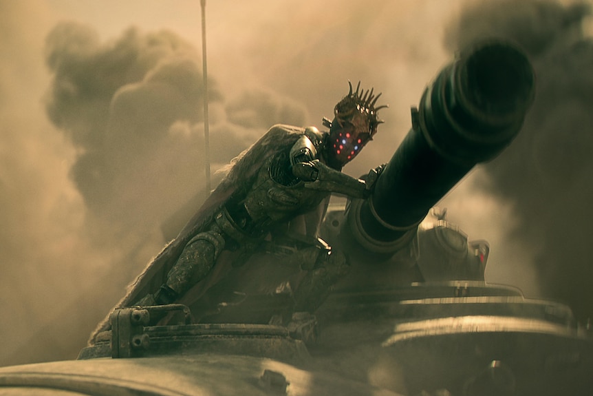Film still of a robot on top of a tank, with huge clouds of dust behind it