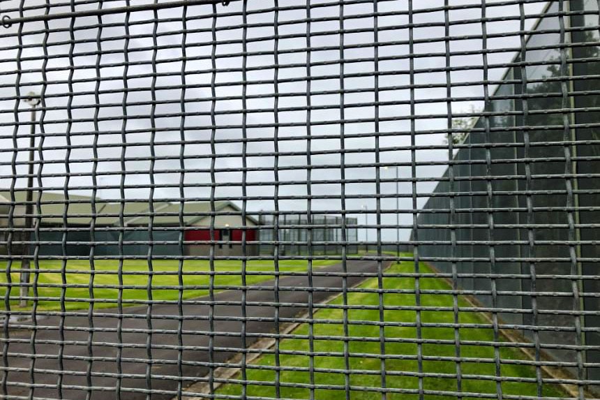 An upclose image of a wall of mesh looking into the detention facility.