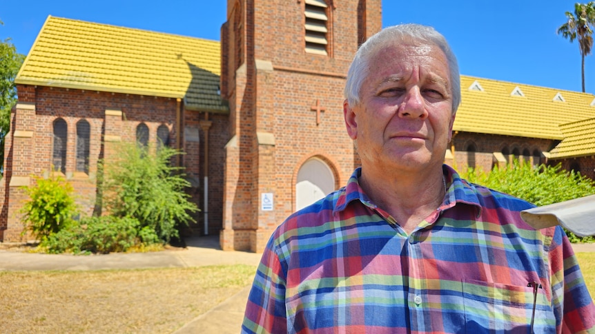 A man standing in front of a church looking unimpressed. 