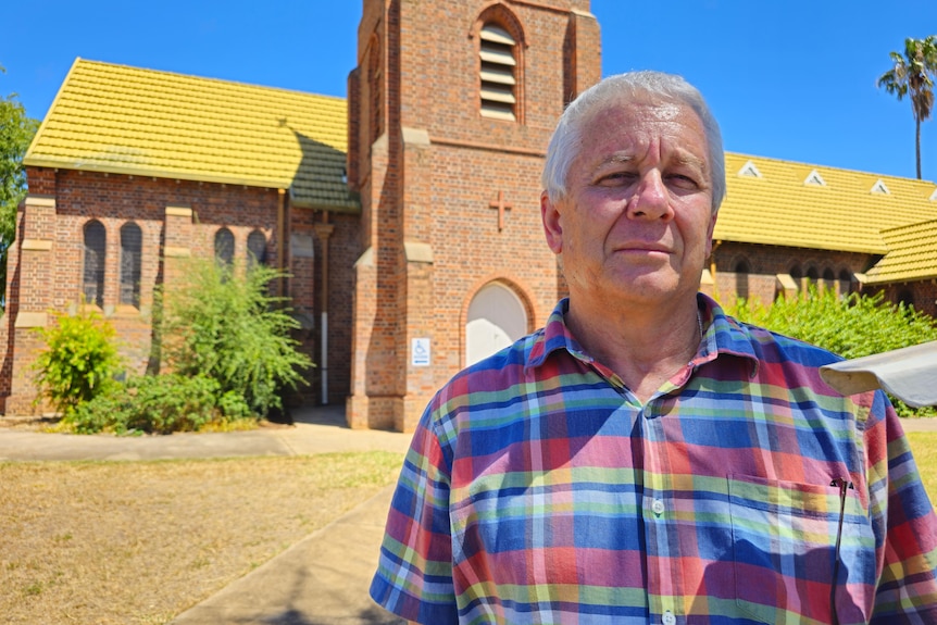 A man standing in front of a church looking unimpressed. 