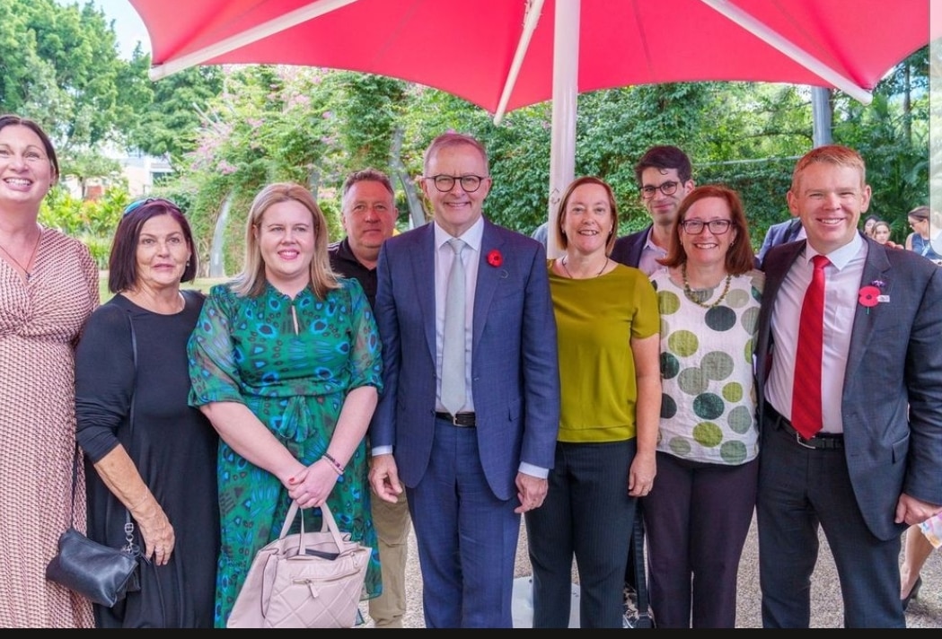 A group of men and women stand alongside the prime minister Anthony Albanese and NZ counterpart Chris Hipkins smiling