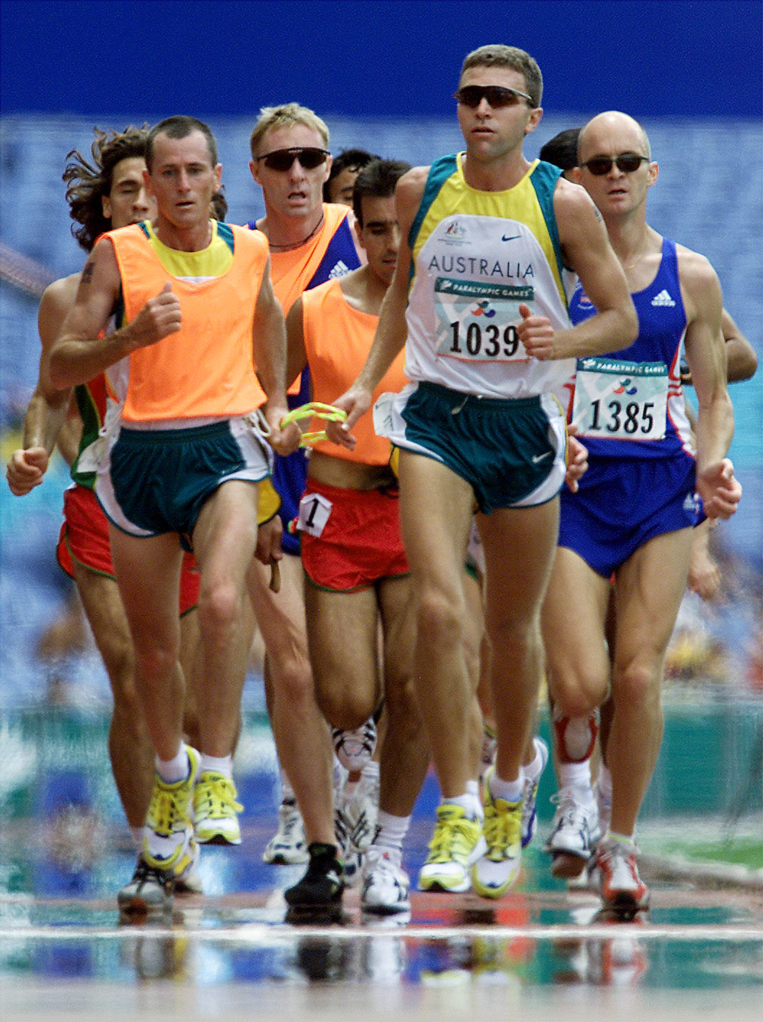 blind runner gerrard gosens holds onto a tether to his guide while in motion on a track at the sydney 2000 olympics