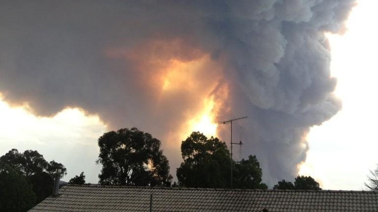 Smoke from a nearby bushfire rises over houses in Coonbarabran in mid January.