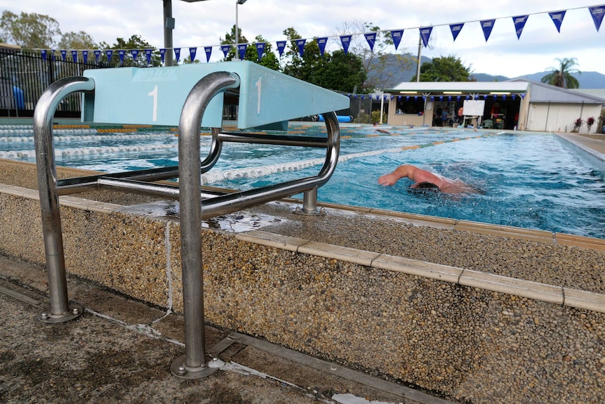 Swimmer approaching diving block at pool.