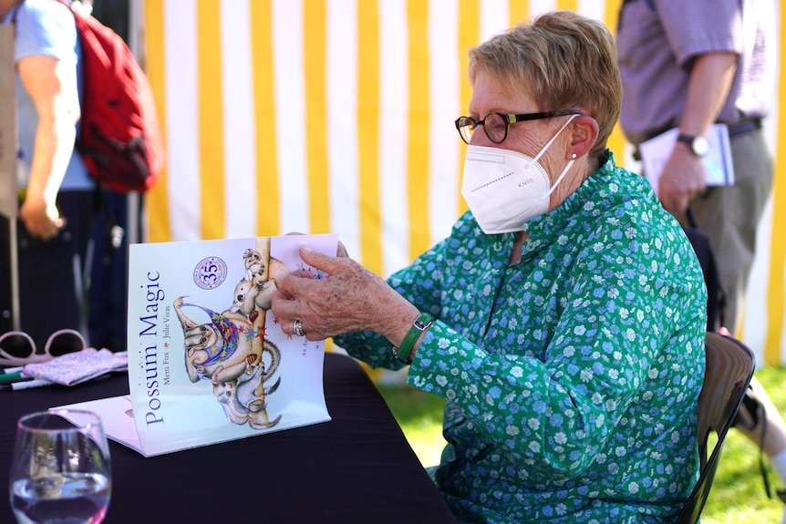 Children's author Mem Fox opens a copy of Possum Magic.