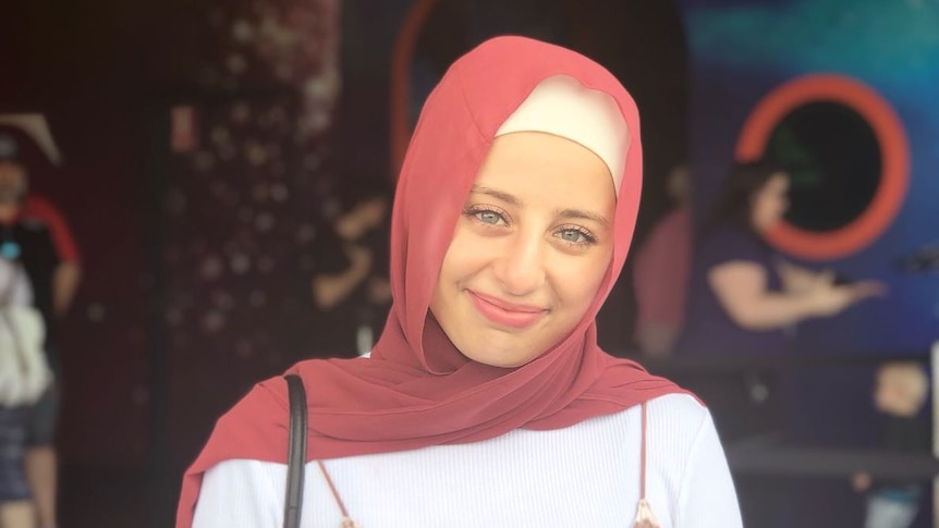 Portrait of Massilia Aili in a pink headscarf and dress smiling