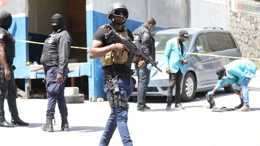 Haitian policeman with helmet and gun standing outside of the presidential residence on July 7, 2021 in Port-au-Prince.