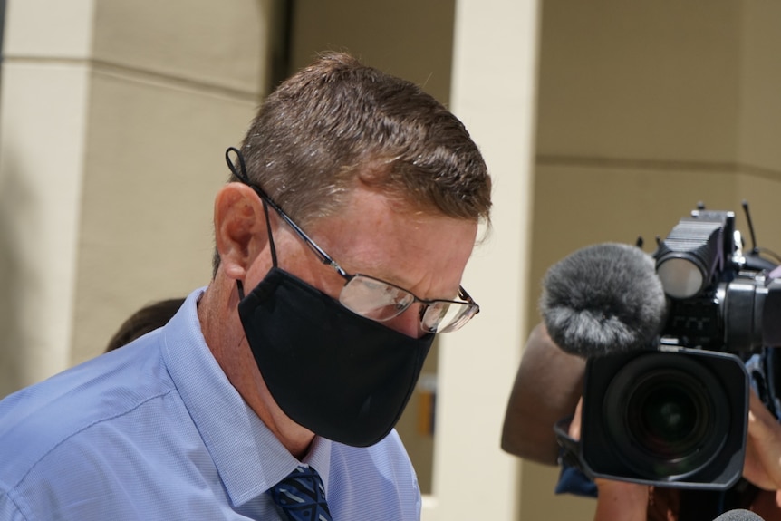 A headshot of a man wearing a face mask.