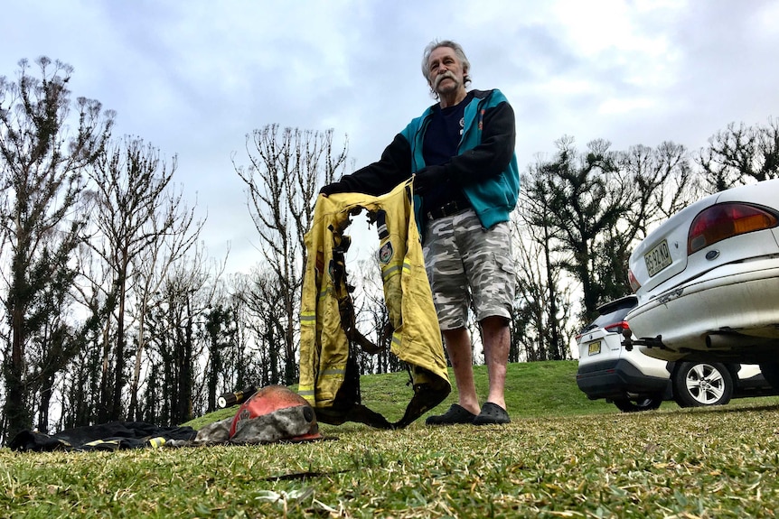 A man holds up a burnt out uniform