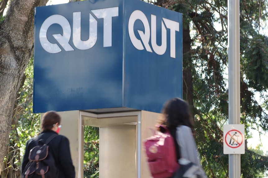 Women walk by QUT sign