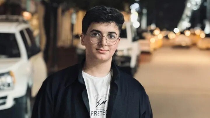 A photo of Noor in Gaza before the war. He's wearing a white shirt, black jacket and glasses.