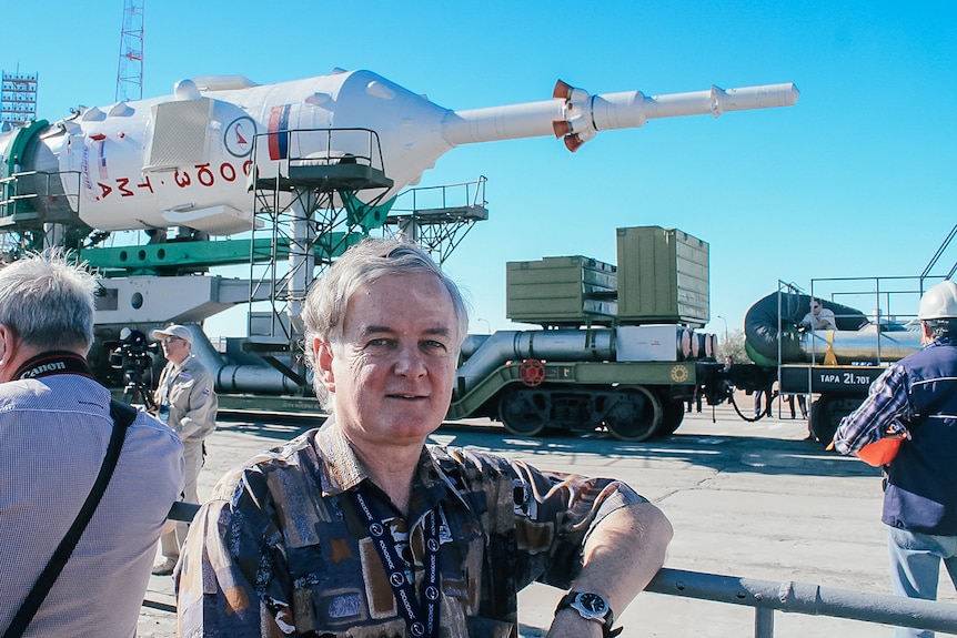 a man stands in front of a rocket