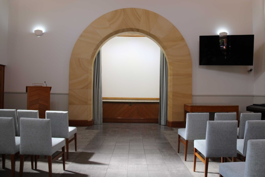 Interior of chapel at a cemetery in Sydney with seats facing a podium and an archway at the front