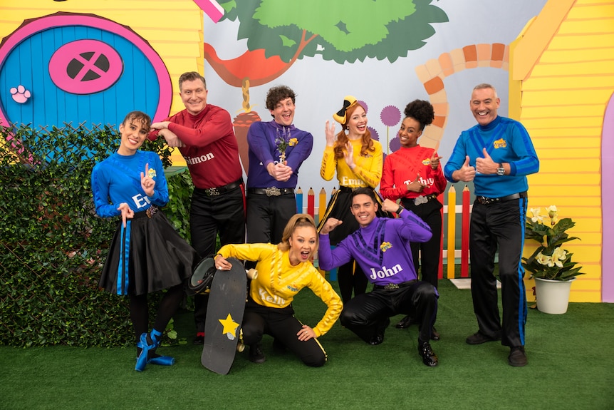 Eight Wiggles dressed in red, blue, purple and yellow skivvies pose together.