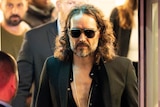 Russell Brand leaves the Troubabour Wembley Park theatre. He is wearing sunglasses at night.