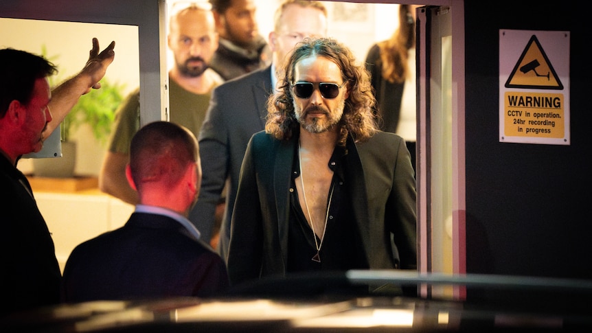 Russell Brand leaves the Troubabour Wembley Park theatre. He is wearing sunglasses at night.