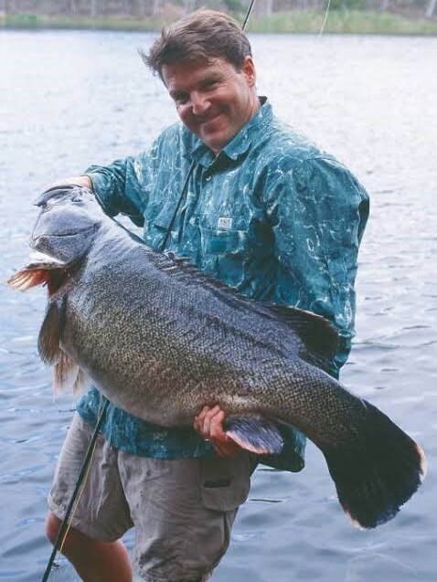 Un hombre sostiene un pez muy grande con ambos brazos.