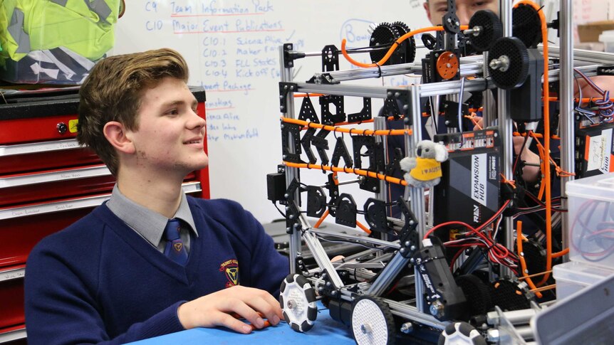 A high school student works on a robot