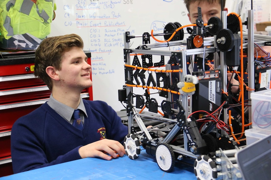 A high school student works on a robot