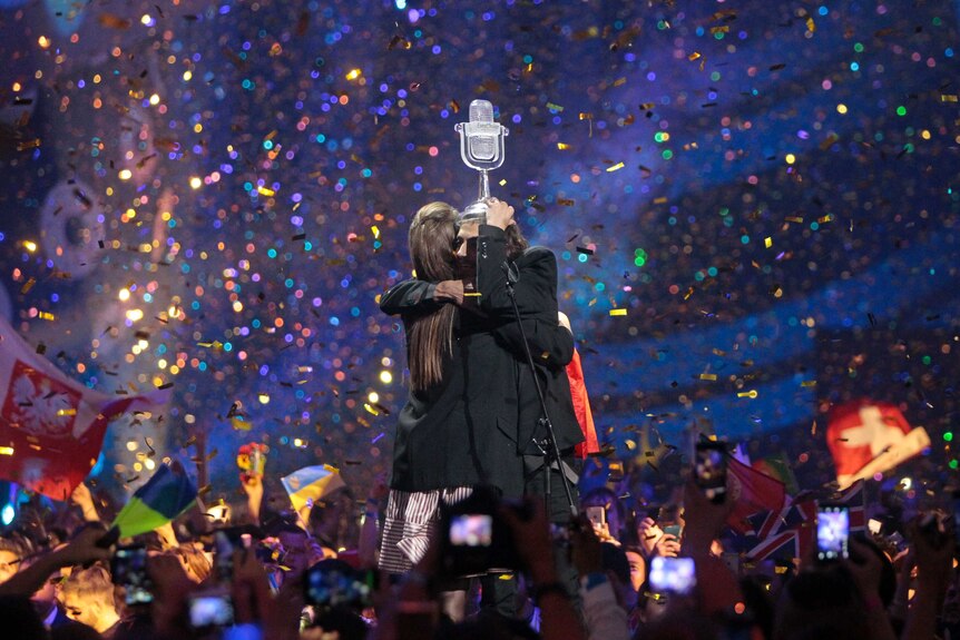 Portugal's Salvador Sobral embraced his sister after the win, holds his trophy above his head as confetti falls on the stage