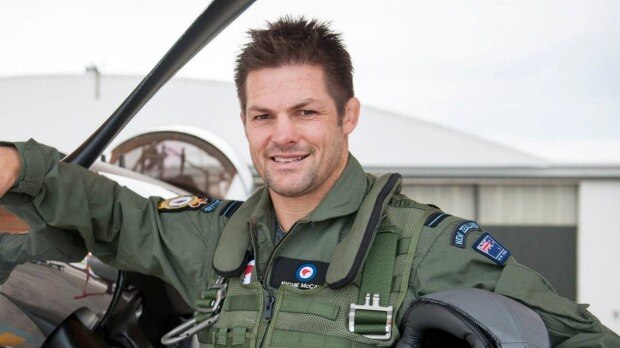 Richie McCaw dressed in uniform at the steering wheel of a helicopter