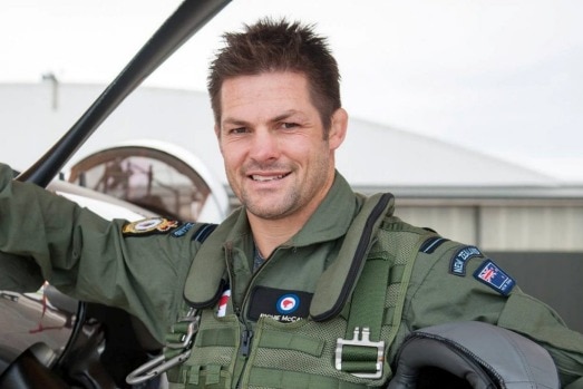 Richie McCaw dressed in uniform at the steering wheel of a helicopter