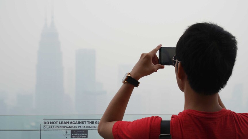 Tourist takes a picture from Kuala Lumpur Tower as city stands shrouded with haze in Kuala Lumpur.