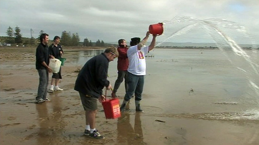 Goolwa locals throw sea water into the lower Murray