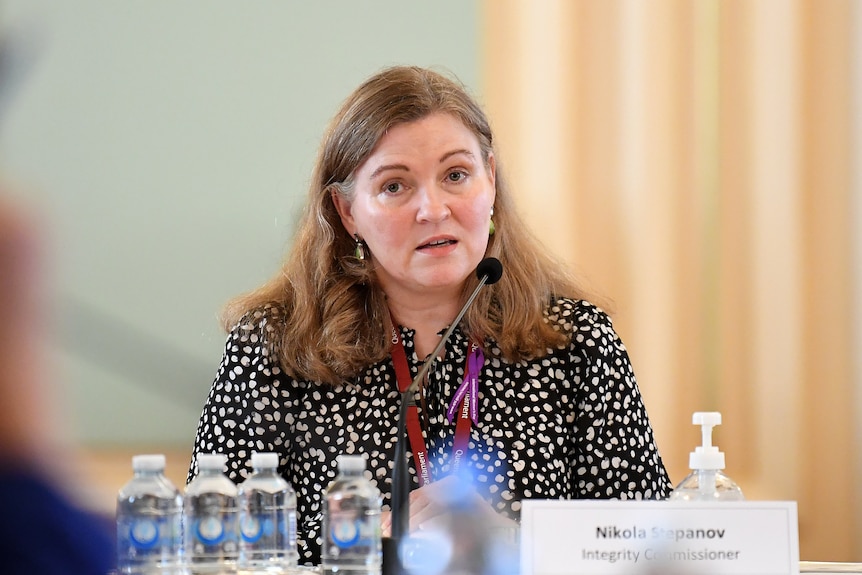 A woman sits before a panel.