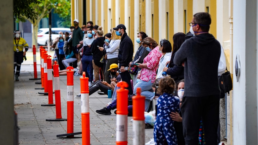 People line up against a building for COVID testing