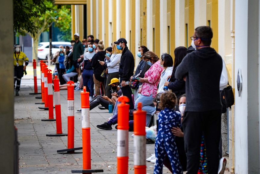 People line up against a building for COVID testing