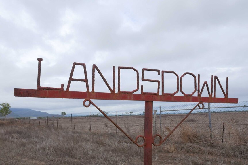 A metal sign in front of a paddock spelling out "Landsdown".