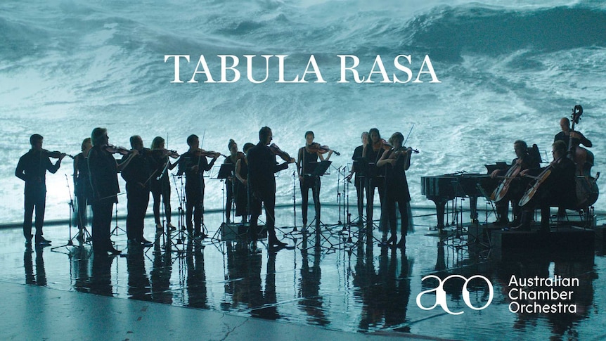 An orchestra playing in front of a projected screen playing video footage of ocean waves
