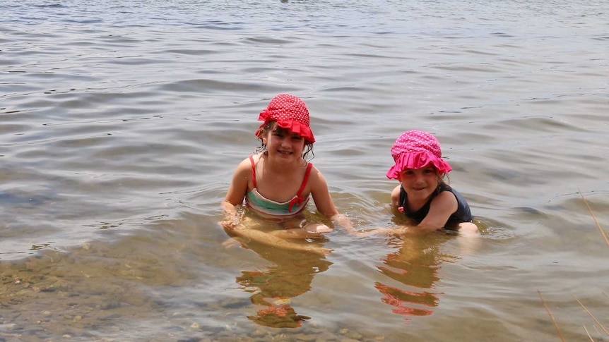 Two children paddle in the lake.