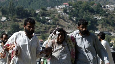 A woman injured in the south Asian earthquake walks with her relatives in the Pakistani town of Balakot.