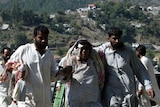 Assistance en route: An injured woman walks with relatives in the earthquake-hit Pakistani town of Balakot.
