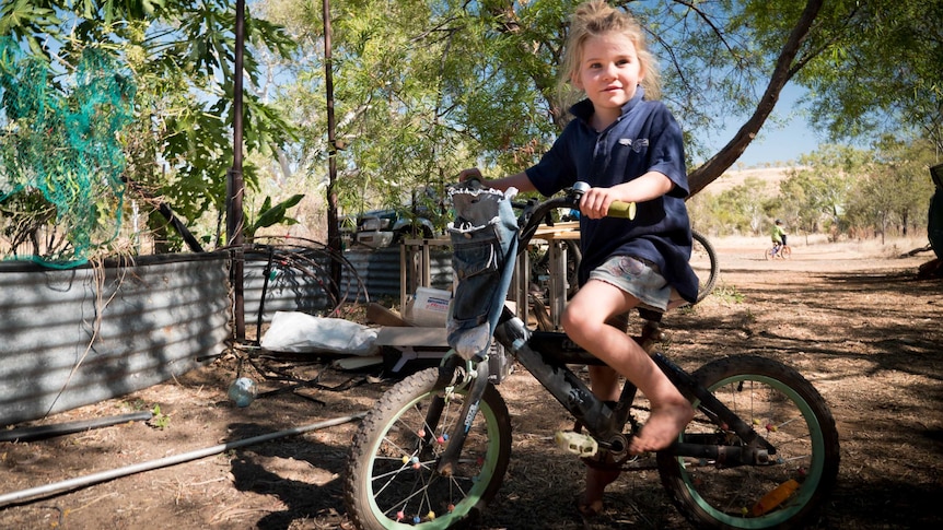 Young girl with blonde hair on a bike outside in the Kimberley.