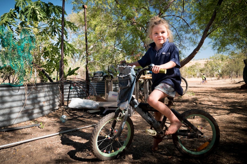 Young girl with blonde hair on a bike outside in the Kimberley.