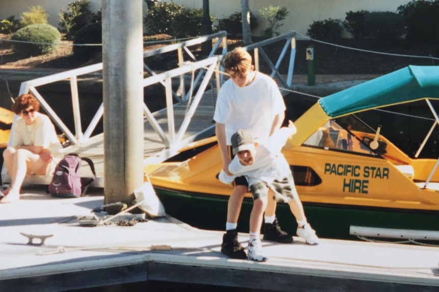 An old film photo of two children playing around near the waterfront.