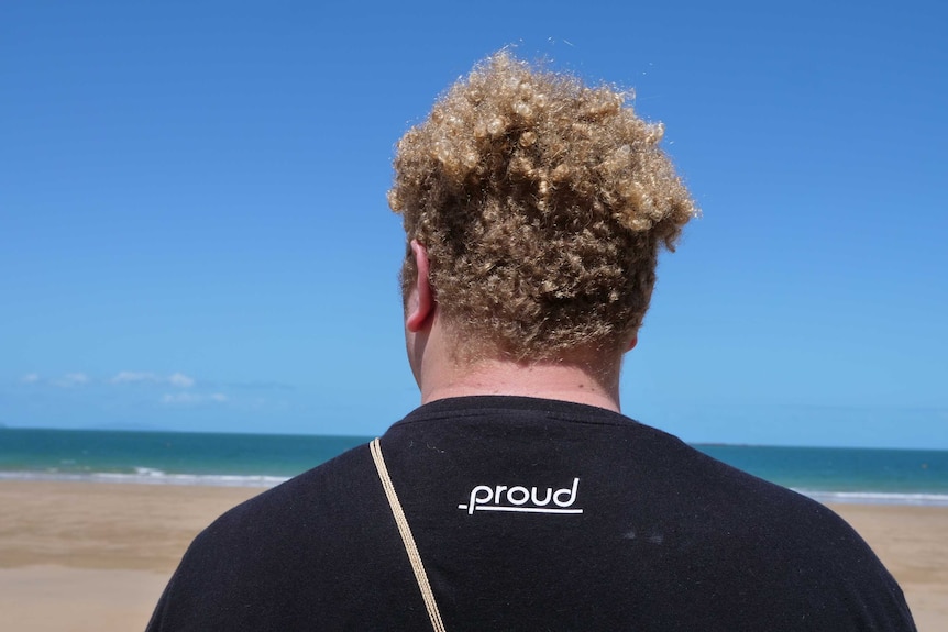 photo take from behind a man looking off into the distance at a beach.
