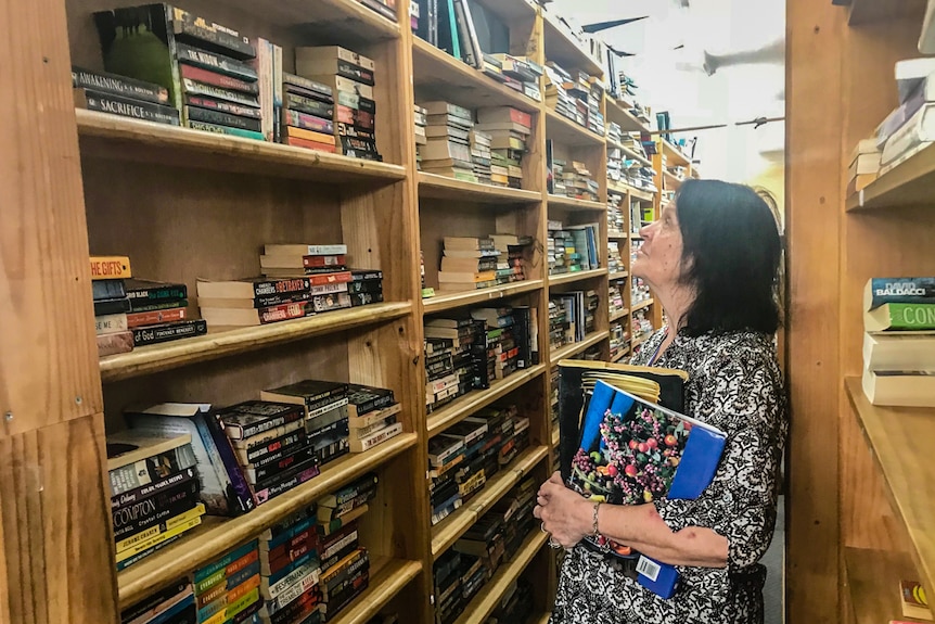 Lady looking at books on shelves.